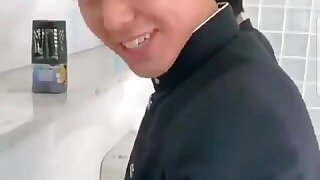 A cute male student is pissing in the toilet.