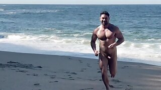 Nude hunk shows off his cock on a beach