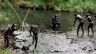 Young Surma boys painting body at the river before de ceremony of stick fighting